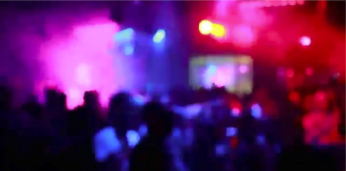 Blurred view of a packed club dancefloor under pink and red lights
